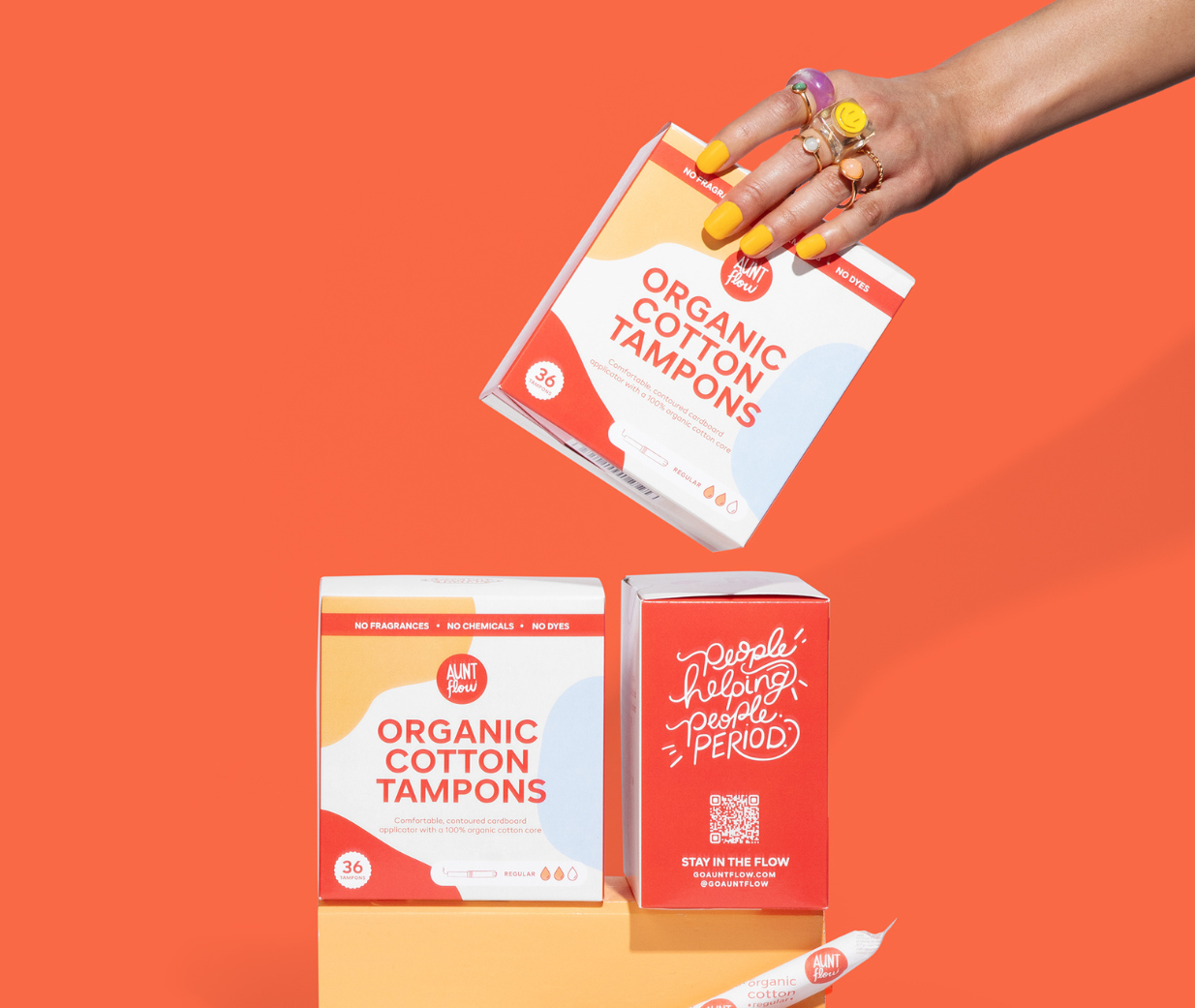 Hand holding organic cotton tampons against an orange background
