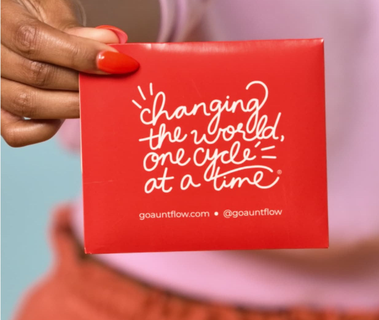 A person holding a red pad cartridge with text 'CHANGING THE WORLD ONE CYCLE AT A TIME' printed on it
