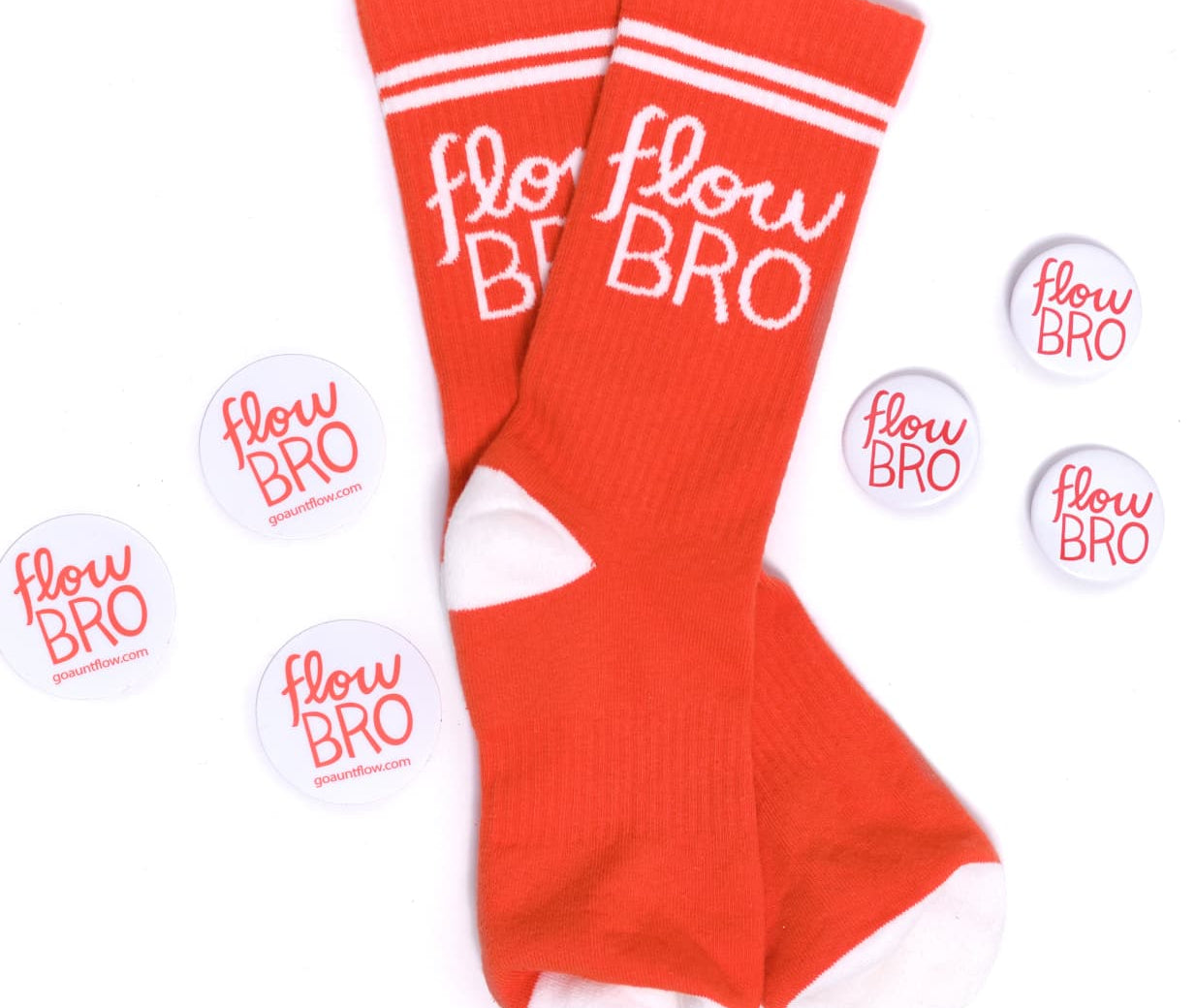 A pair of bright red crew socks with white stripes at the top and white toes/heels, featuring the text 'flow BRO' in white script. Several matching round stickers with the same design are arranged around them on a plain white background.